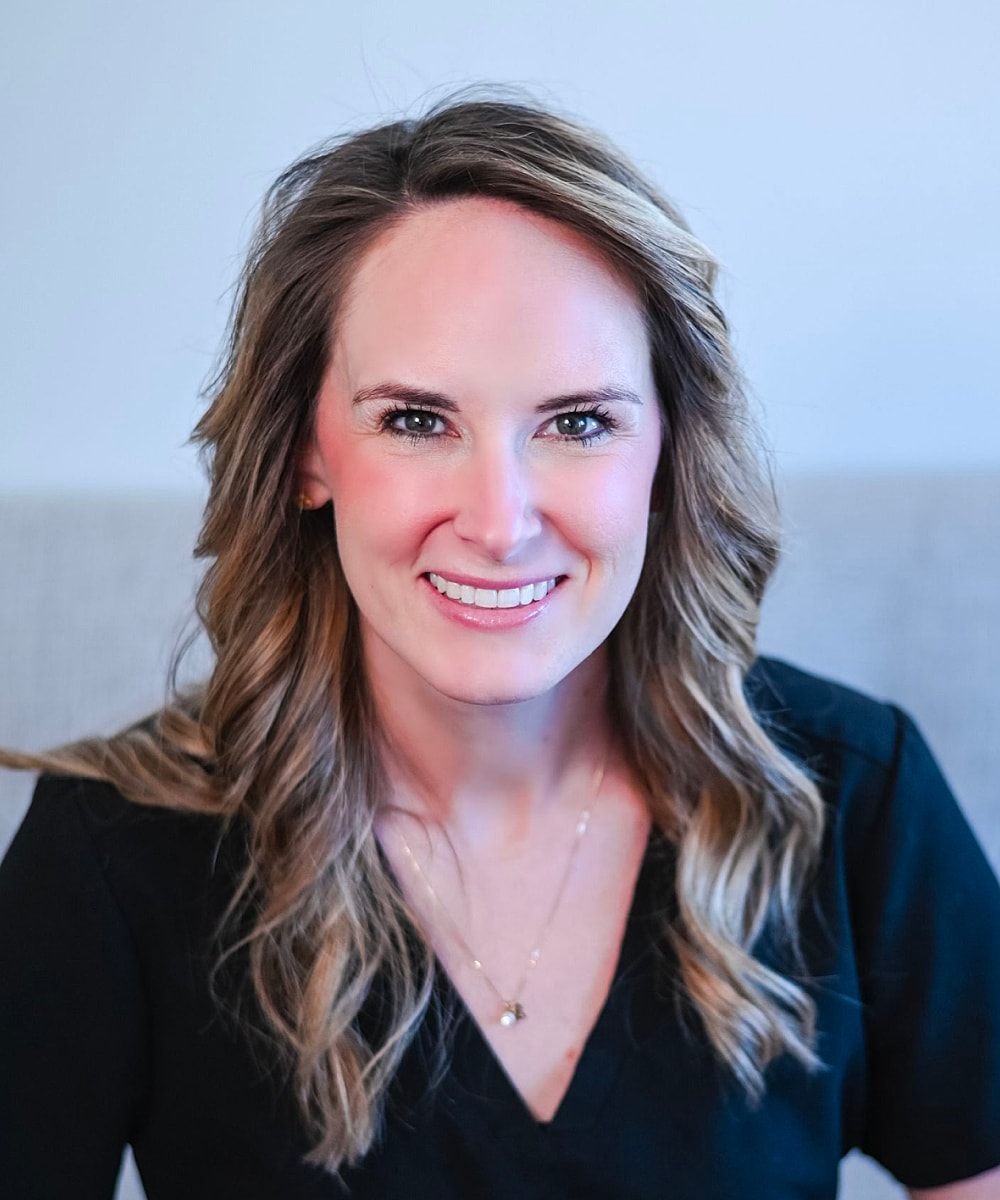Woman smiling in professional attire, light background.