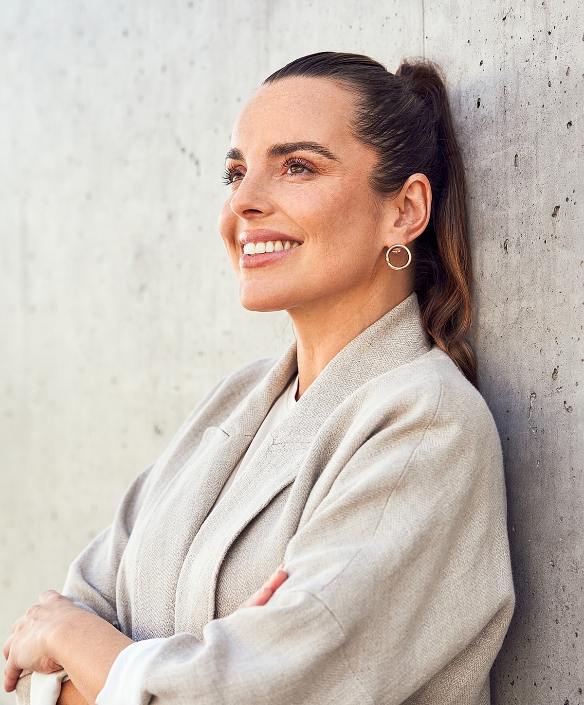 Smiling woman leaning against textured wall.