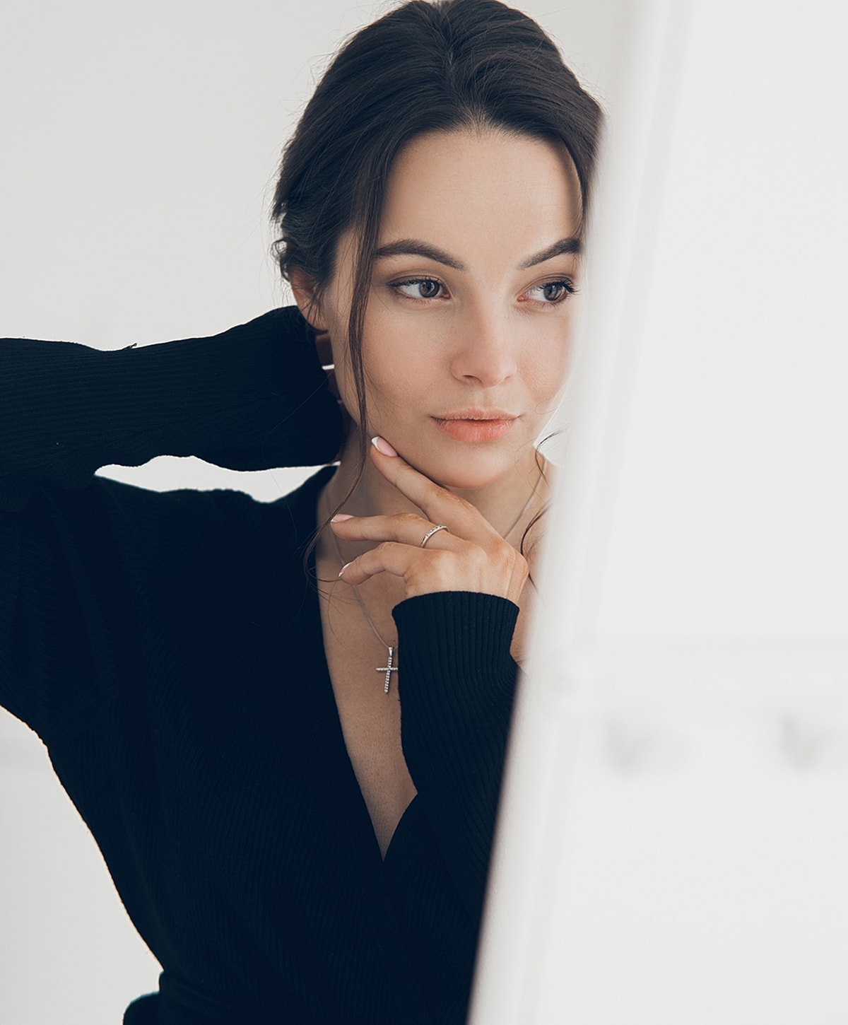 Woman posing thoughtfully in a black sweater.