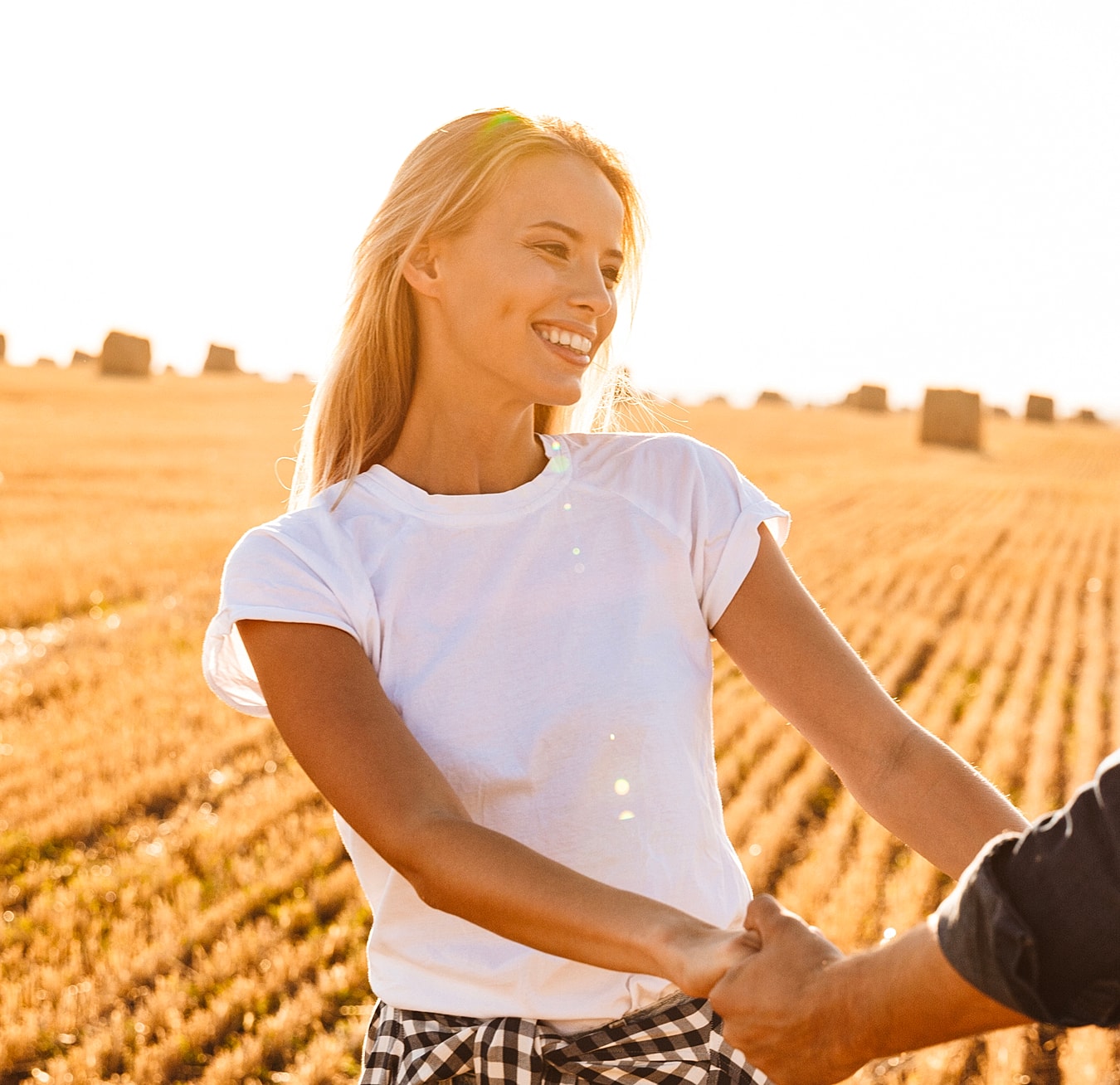 Smiling woman holding hands in golden field.