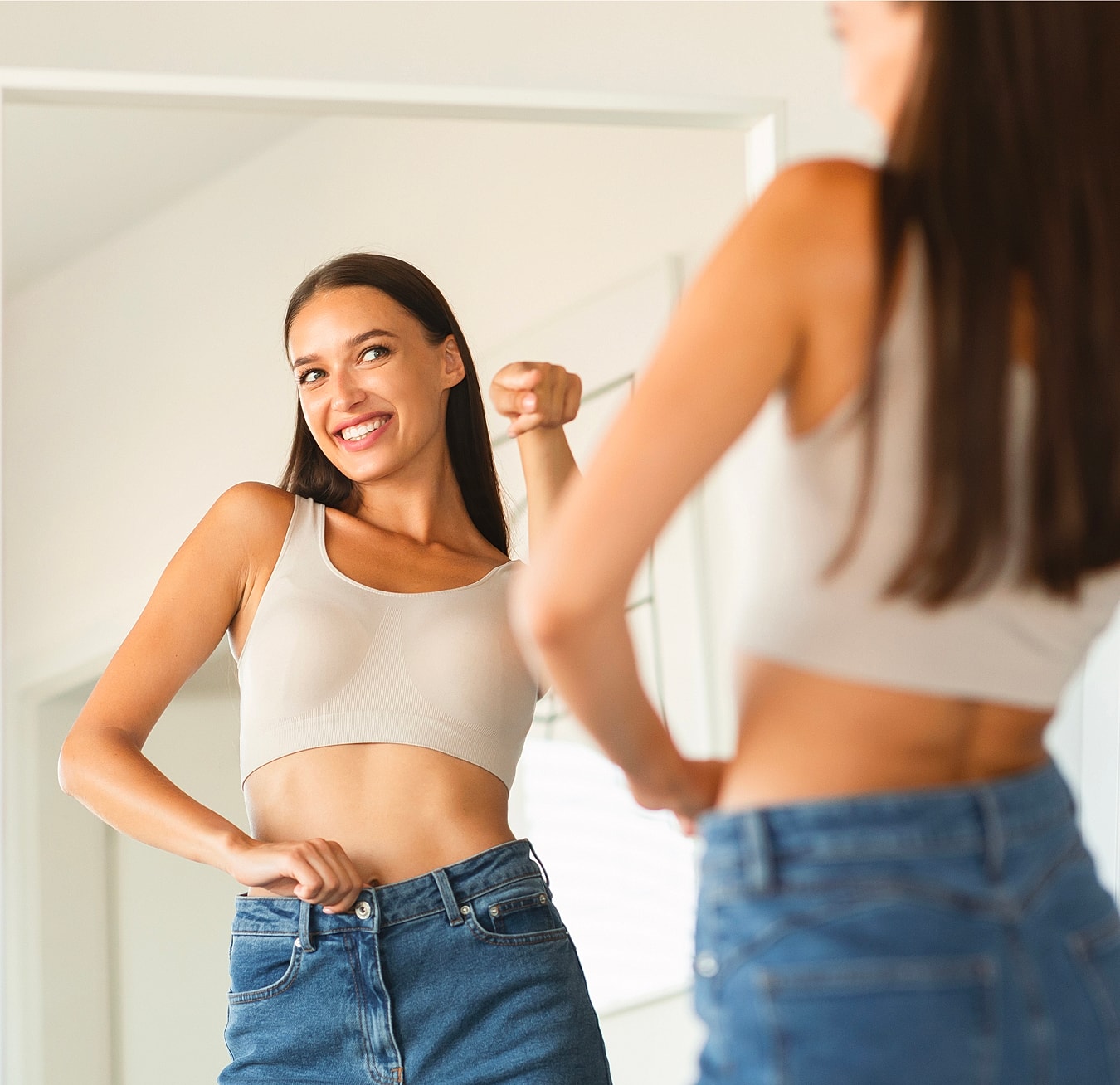 Woman admiring outfit in mirror, smiling happily.