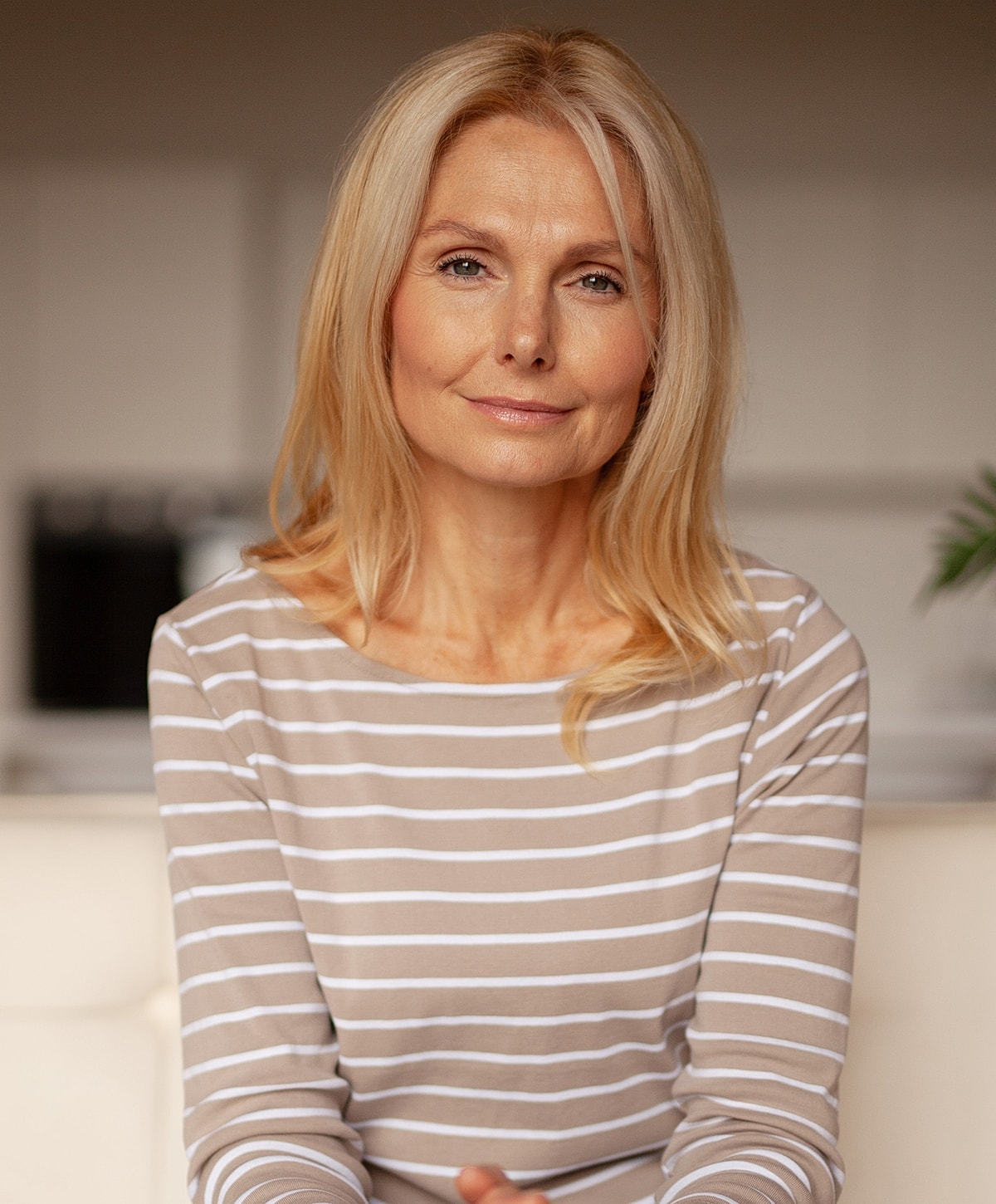 Smiling woman with long blonde hair indoors.