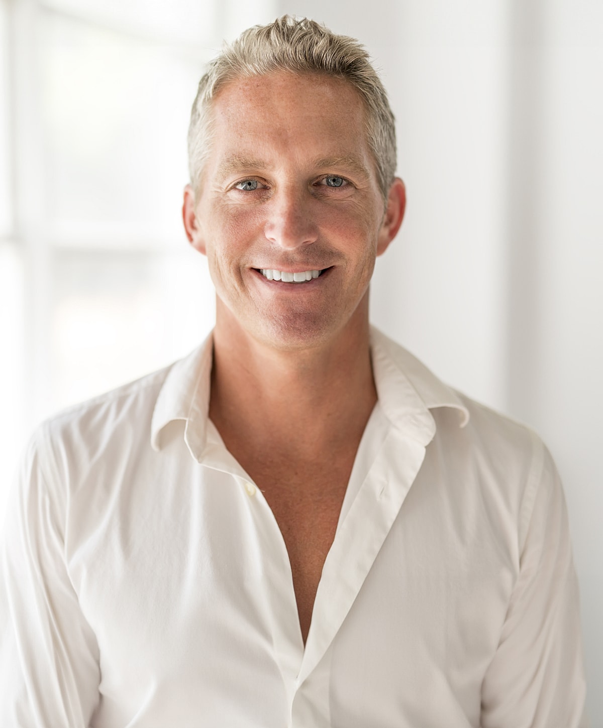 Smiling man in a white shirt, bright background.