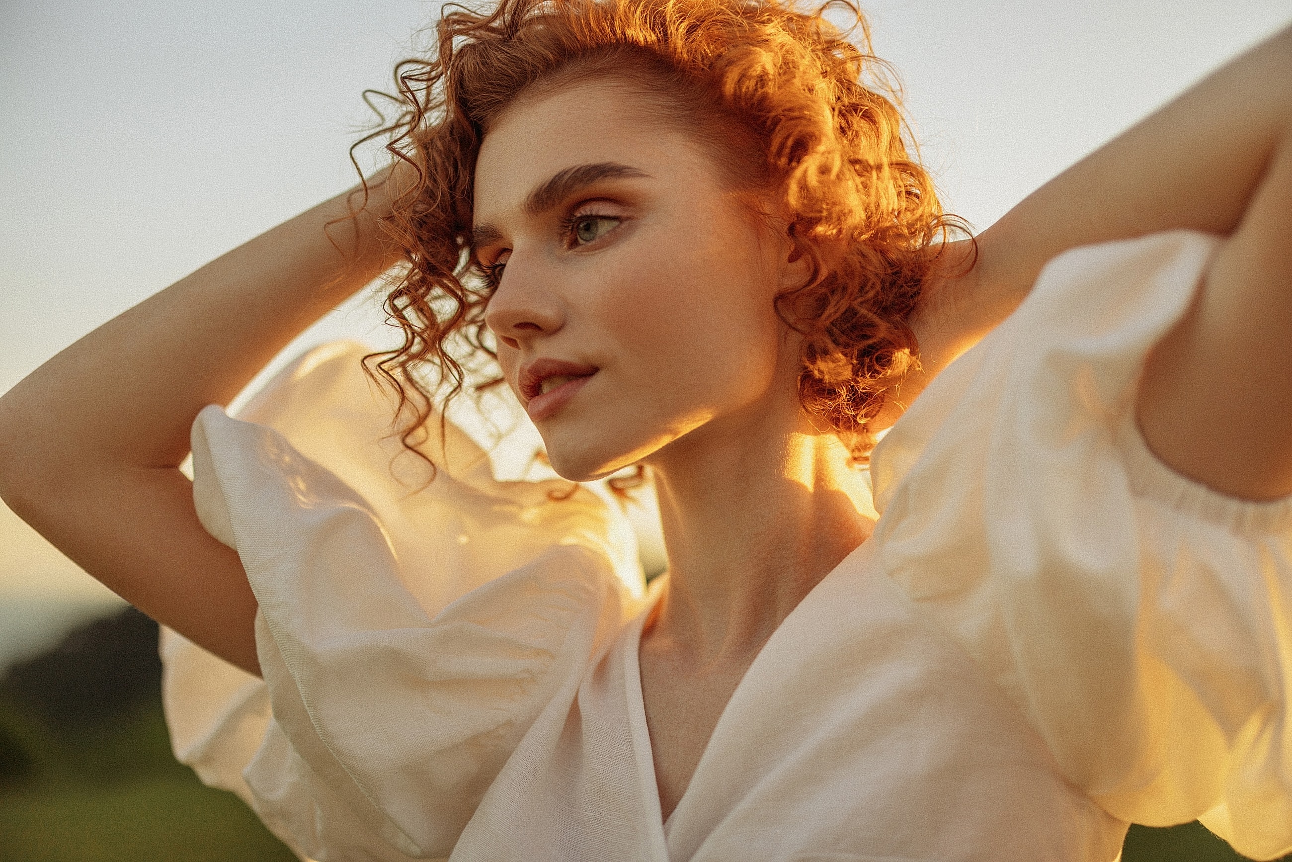 Woman with curly hair in sunlight background.