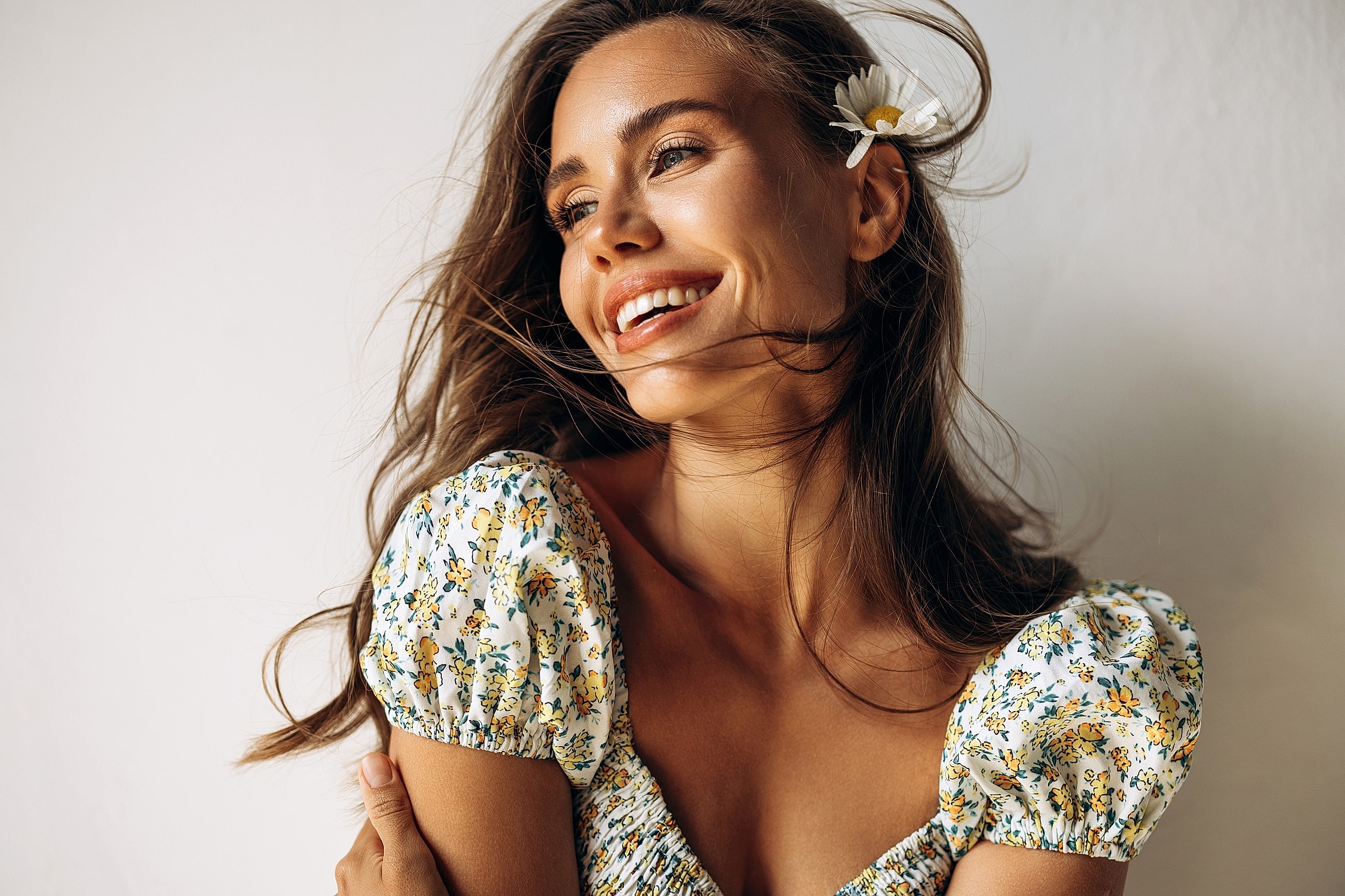 Smiling woman with flower in hair, natural light.