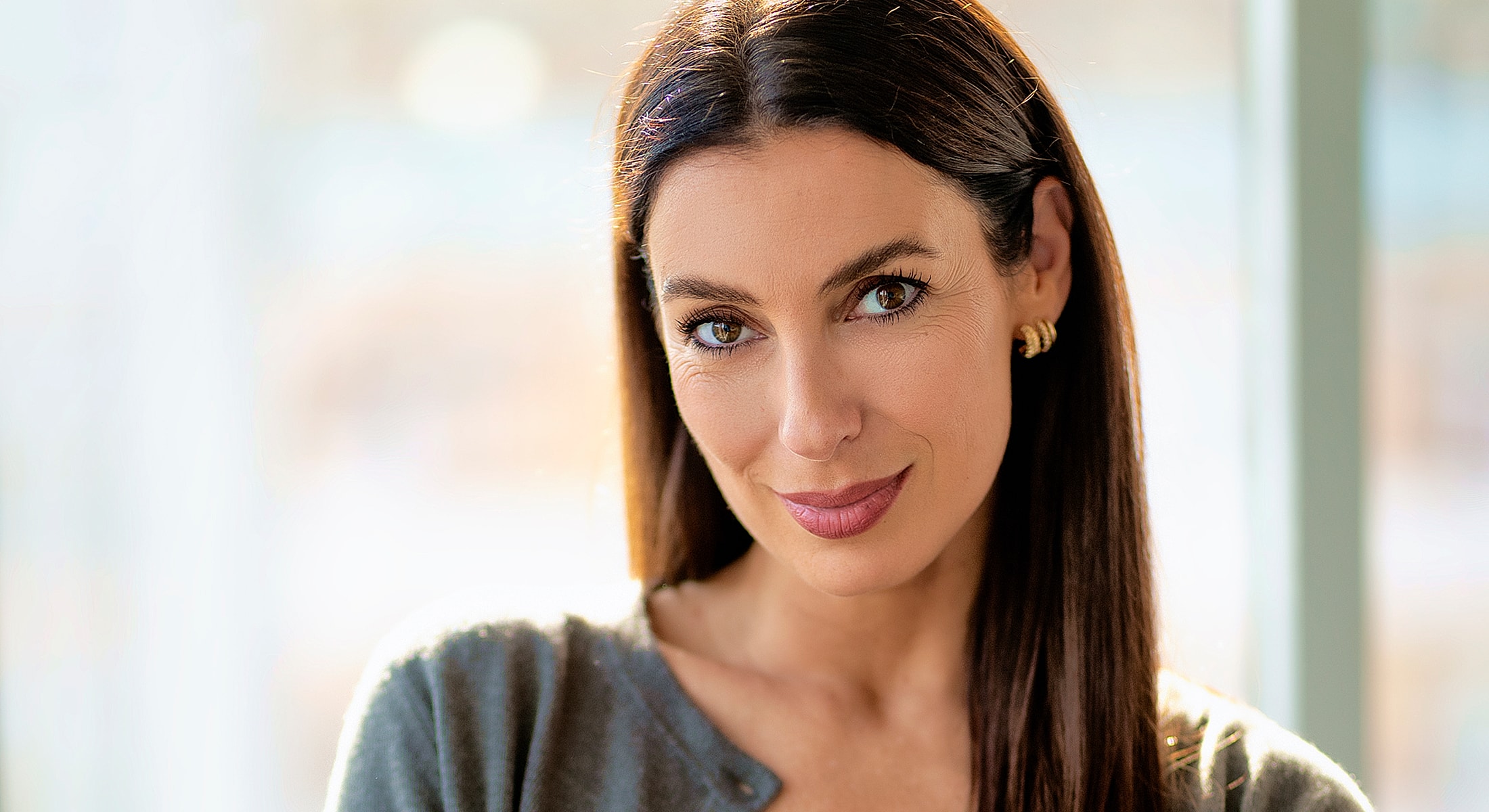 Smiling woman in a bright, soft setting.