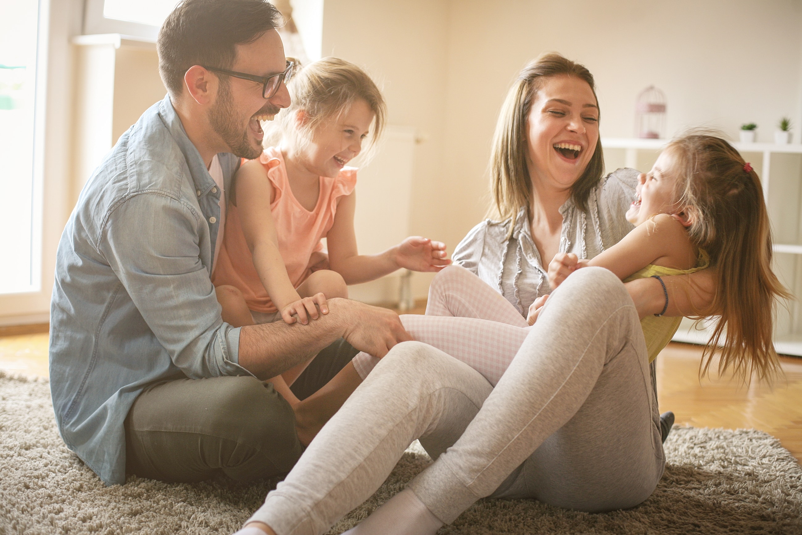 Family playing and laughing together indoors.
